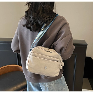 Détail du sac bandoulière en nylon kaki avec zips multicouches et sangle en jacquard