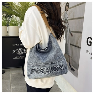 Side view of a vintage wash denim hobo bag with adjustable brown strap on a model