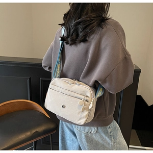 Détail du sac bandoulière crème multi-poches avec large sangle à motifs