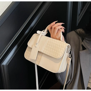 Close-up of cream woven leather handbag with metallic buckles and shoulder strap detail