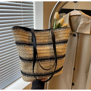 Détail du sac cabas tissé avec rayures noires horizontales et fines anses en cuir noir