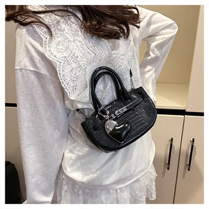 Detail of black crocodile pattern mini handbag with heart charm and silver metal lock
