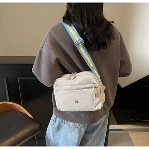 Détail du sac bandoulière en nylon gris clair avec compartiments zippés multicouches