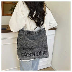 Close-up of vintage washed grey denim tote bag with embossed fashion letter detail