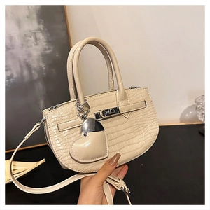 Detail of cream crocodile pattern handbag with silver heart charm and metal buckle