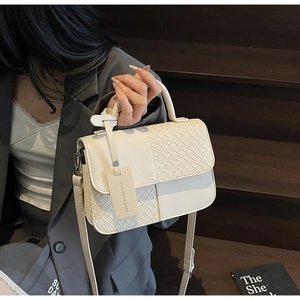Detail of cream woven crossbody bag with silver hardware on a professional model