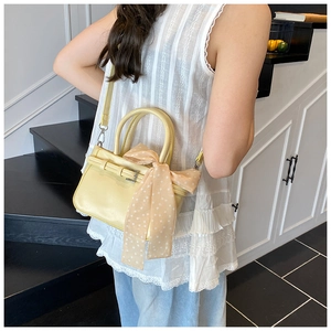 Detailed view of cream yellow crossbody bag with polka dot scarf on a model
