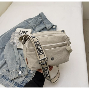 Vue détaillée du sac beige multicouche avec bandoulière large et poches zippées