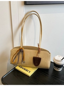 Sac baguette minimaliste crème avec ruban de soie décoratif sur une table noire