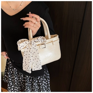 Close-up of cream patent leather handbag with polka dot silk scarf and buckle detail