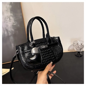 Close-up of black crocodile pattern leather handbag featuring a unique heart charm detail