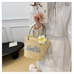 Strohtasche mit Hello-Stickerei und Frangipani-Blume auf weißem Hintergrund im Detail