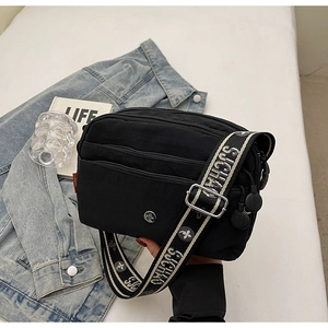 Détail du sac bandoulière noir multi-poches avec large bandoulière à logo stylé
