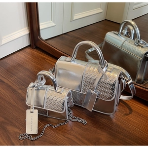 Detail view of two silver metallic handbags with woven texture and fashion tag