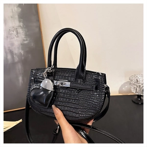 Detail of black crocodile pattern handbag with silver hardware and heart charm pendant