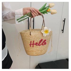 Detail der Strohtasche mit Hello-Stickerei, Frangipani-Blüte und Kordelzug-Innentasche