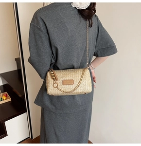 Détails de la texture paille d'un sac beige avec une bandoulière en chaîne dorée