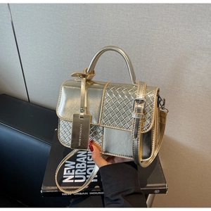 Detailed shot of golden metallic PU leather bag with woven texture and top handle