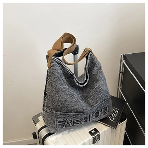 Detail of washed grey denim tote bag with FASHION embossing and woven strap