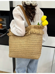 Retro woven straw tote bag with brown leather handles and decorative fringe trim