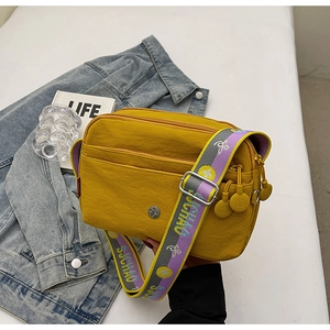 Détail du sac bandoulière en nylon jaune avec sangle à motifs et logo en métal