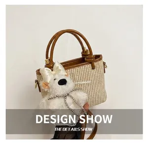 Detail of beige woven bucket bag with brown leather handles and a cute puppy charm