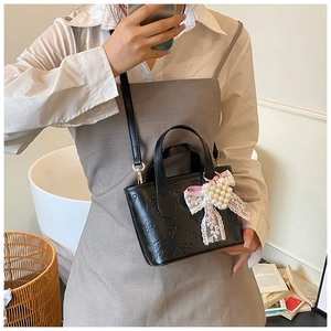Detail of black embossed butterfly bucket bag with lace bow and pearl charm pendant