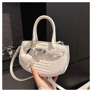 Detailed macro view of white crocodile pattern texture and silver heart charm on handbag