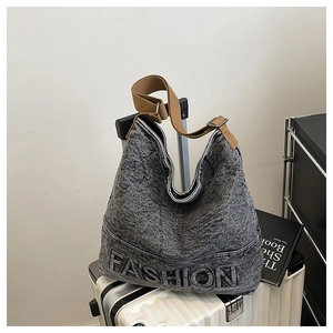 Close-up of washed denim tote bag featuring embossed FASHION text and brown canvas strap