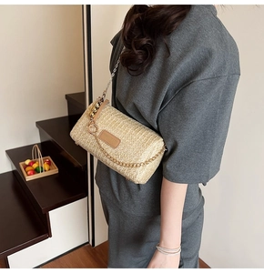 Detail of beige woven cylinder bag with gold chain strap and pearl bead charm
