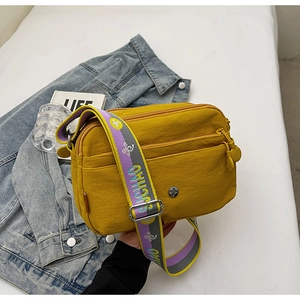 Vue détaillée du sac bandoulière jaune en nylon avec trois poches zippées et sangle large