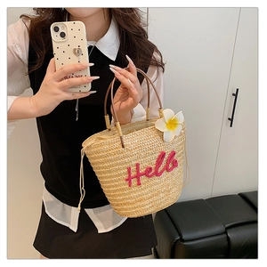 Detail der Strohtasche mit rosa Hello-Stickerei und einer tropischen Plumeria-Blume