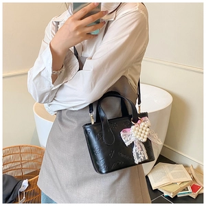Detail of black embossed PU bucket bag with floral patterns and a pearl heart charm