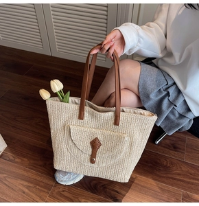 Detail of hand-woven straw tote bag with brown straps and elegant herringbone pattern