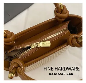 Macro detail of gold-tone zipper and brown leather trim on beige woven handbag