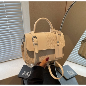 Detail of cream white leather crossbody bag with woven texture and fashion tag
