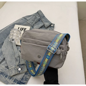 Détail du sac bandoulière gris avec une large bandoulière jacquard imprimée tendance