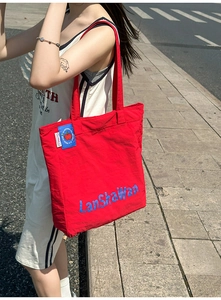 Gros plan d'un sac cabas en nylon rouge avec broderie LanShaWan bleue et détails d'étiquette