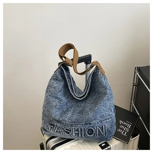 Detail of denim tote bag with FASHION embroidery and adjustable brown strap