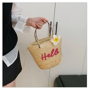 Detail der Strohhandtasche mit roter Hello-Stickerei und weißer Plumeria-Blumenverzierung