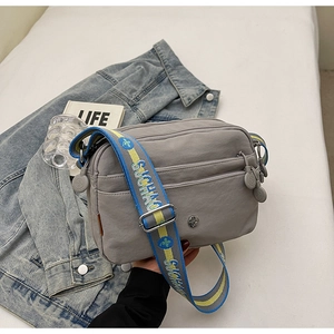 Détails du sac bandoulière gris en nylon avec poches zippées et sangle en tissu lettré