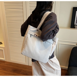 Lifestyle view of large beige canvas tote bag with shoulder straps and outer pocket