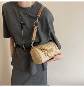 Detailed macro view of woven straw texture and leather logo patch on a cylindrical bag