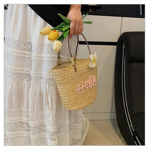 Detailansicht der Strohhandtasche mit rosa Hello-Stickerei und Tropenblumen-Akzent