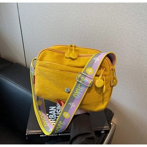 Détail du sac bandoulière en nylon jaune vif avec poches zippées et sangle large