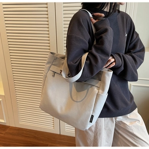 Side view of large light grey canvas tote bag with side pocket shown on model