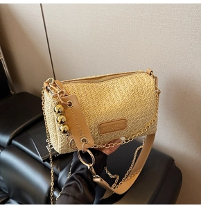 Détail du sac en paille tressée avec sphères dorées et bandoulière en PU marron chic