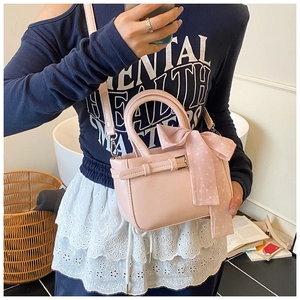 Pink minimalist square bag with polka dot scarf detail and crossbody strap worn by model