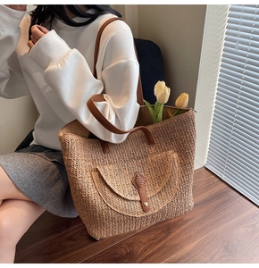 Detailed view of woven straw tote bag featuring leather front pocket and top handles