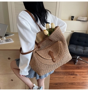 Close-up of woven straw tote bag with brown leather straps and tulip flower decorations